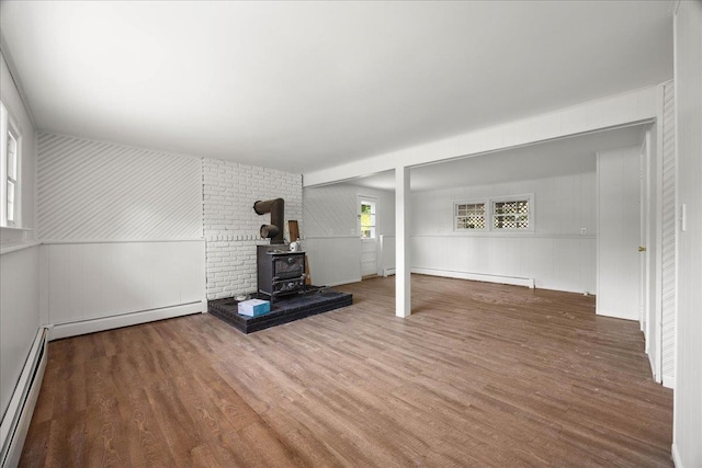 15 Mari Rd, Chester, NY 10918 - unfurnished living room with a wood stove, a baseboard radiator, wood finished floors, and a decorative wall