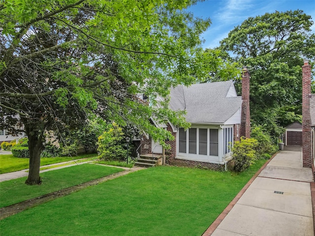 155 Carman Ave, East Rockaway, NY 11518 - obstructed view of property featuring a front lawn, an outdoor structure, a shingled roof, brick siding, and a garage