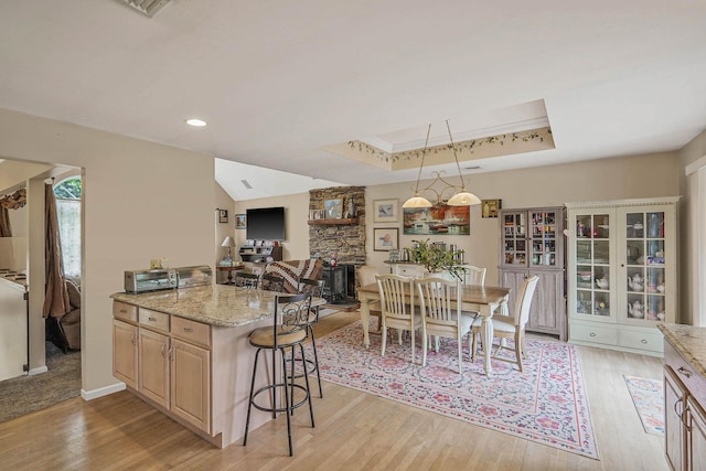 14 Arlington St, Patchogue, NY 11772 - kitchen with a breakfast bar, light wood-style floors, light stone counters, a tray ceiling, and decorative light fixtures