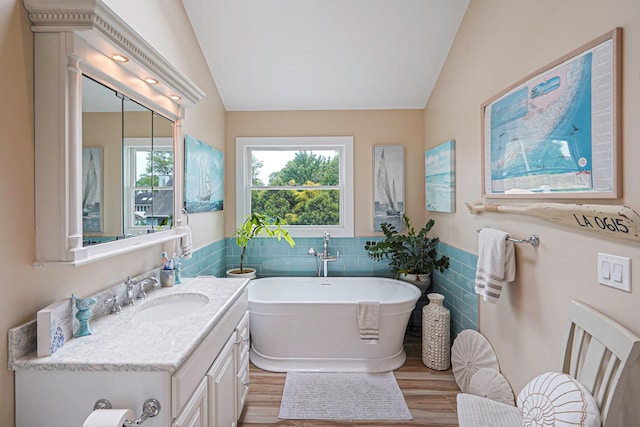 14 Arlington St, Patchogue, NY 11772 - bathroom featuring vaulted ceiling, vanity, a freestanding bath, tile walls, and wood finished floors