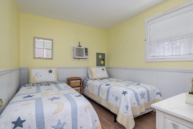 25 Cottage Rd, Baiting Hollow, NY 11933 - bedroom featuring a wainscoted wall, multiple windows, wood finished floors, and a wall mounted air conditioner