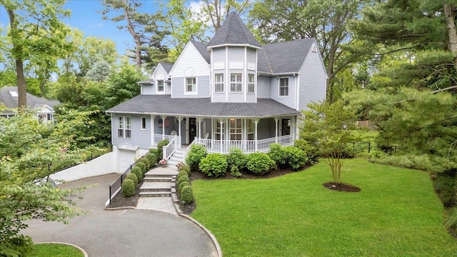 57 Harbor Park Dr, Centerport, NY 11721 - victorian house featuring a porch, asphalt driveway, a front lawn, a garage, and a shingled roof