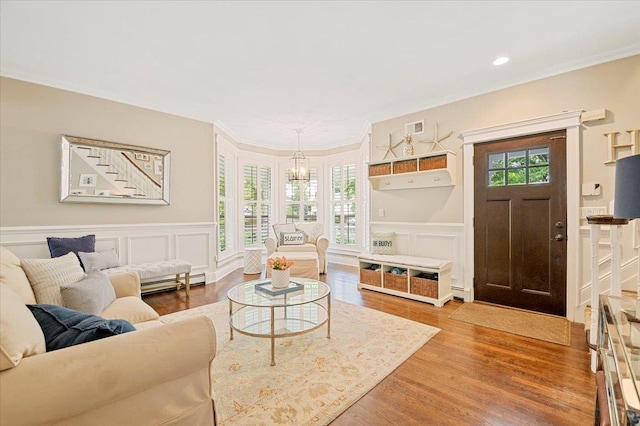 57 Harbor Park Dr, Centerport, NY 11721 - living room featuring a chandelier, wood finished floors, a decorative wall, baseboard heating, and a wainscoted wall