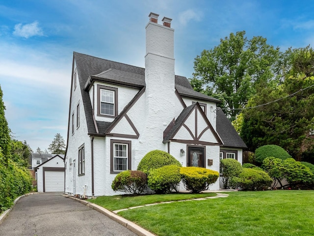 62 Webster Ave, Manhasset, NY 11030 - tudor-style house with a front yard, a shingled roof, asphalt driveway, stucco siding, and a garage