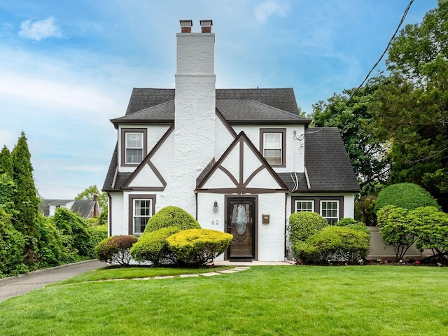 62 Webster Ave, Manhasset, NY 11030 - english style home with a front lawn, a chimney, roof with shingles, and stucco siding