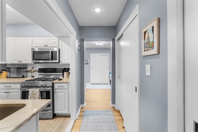 120 E Hartsdale Unit 3L, Hartsdale, NY 10530 - kitchen with appliances with stainless steel finishes, light stone countertops, white cabinets, and light wood-style flooring