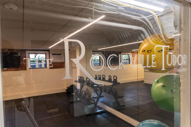 gym featuring a wall unit AC and baseboards