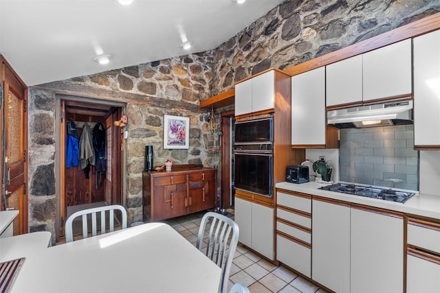 1670 Baptist Church Rd, Yorktown Heights, NY 10598 - kitchen with under cabinet range hood, gas cooktop, black oven, white cabinetry, and light countertops