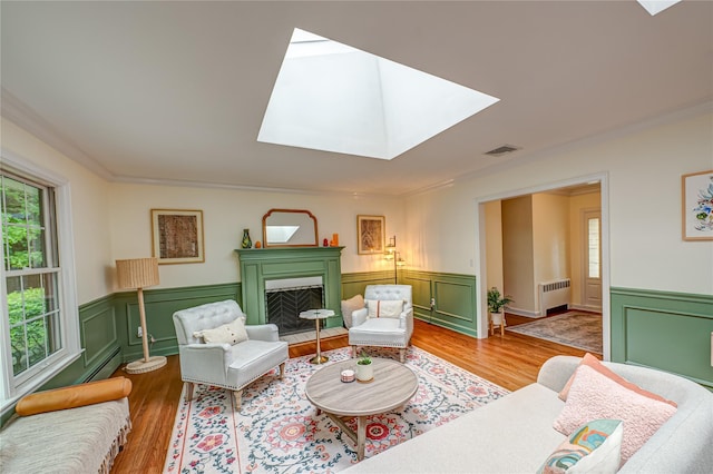1 Idle Day Dr, Centerport, NY 11721 - living area with radiator, a skylight, wood finished floors, wainscoting, and crown molding