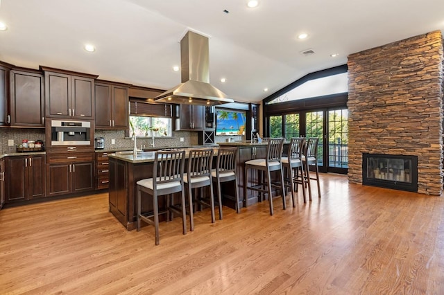 135 Ocean Ave, Massapequa, NY 11758 - kitchen featuring island range hood, a breakfast bar, light wood finished floors, healthy amount of natural light, and lofted ceiling