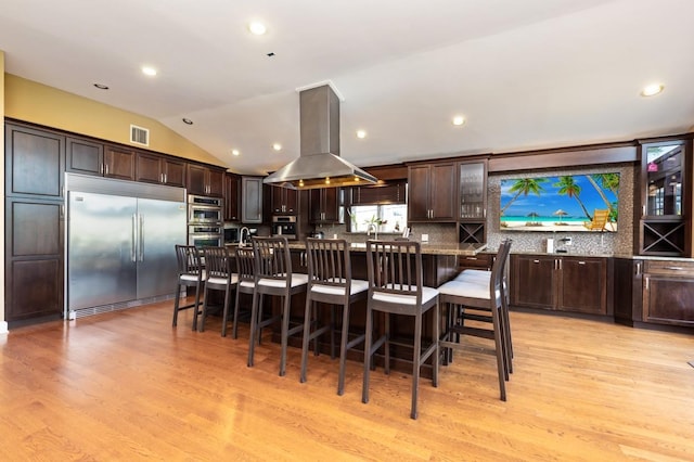 135 Ocean Ave, Massapequa, NY 11758 - kitchen featuring appliances with stainless steel finishes, island exhaust hood, dark brown cabinetry, light wood-type flooring, and lofted ceiling