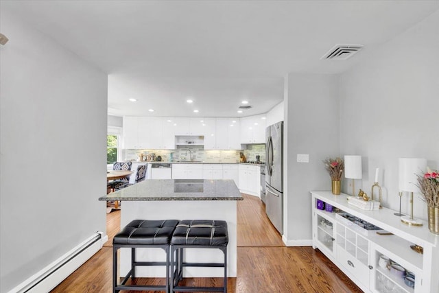 1223 Weaver St, New Rochelle, NY 10804 - kitchen with baseboard heating, white cabinetry, a sink, a breakfast bar, and tasteful backsplash