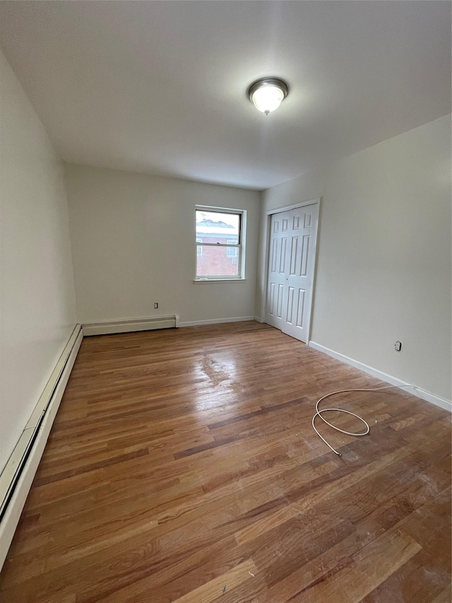2110 Light St, Bronx, NY 10466 - unfurnished bedroom with baseboard heating, wood finished floors, a closet, and baseboards