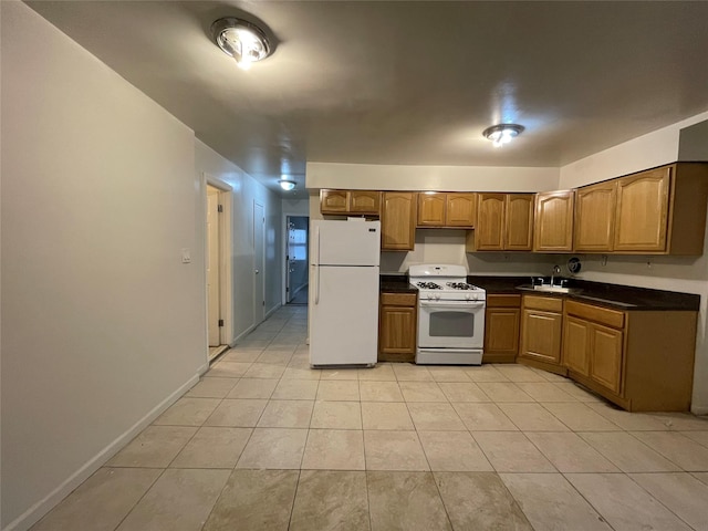 2110 Light St, Bronx, NY 10466 - kitchen featuring white appliances, dark countertops, light tile patterned floors, a sink, and brown cabinets