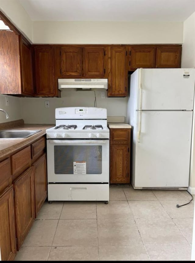 2110 Light St, Bronx, NY 10466 - kitchen featuring white appliances, under cabinet range hood, light tile patterned flooring, a sink, and brown cabinets