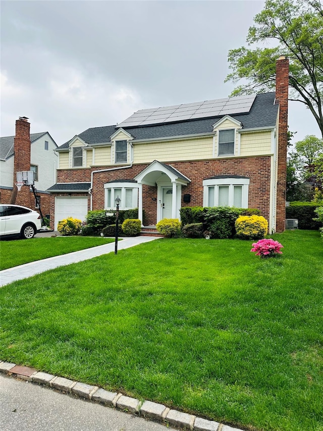 16 Andover Ln, Manhasset, NY 11030 - view of front of property featuring solar panels, a front lawn, an attached garage, and brick siding