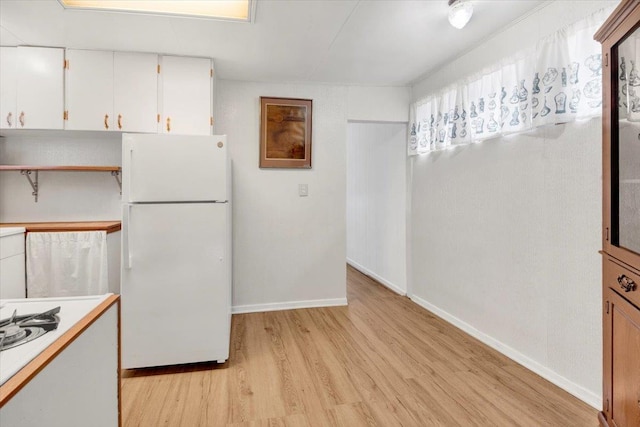 611 Clarence Ave, Bronx, NY 10465 - kitchen with freestanding refrigerator, light wood finished floors, light countertops, white cabinetry, and baseboards
