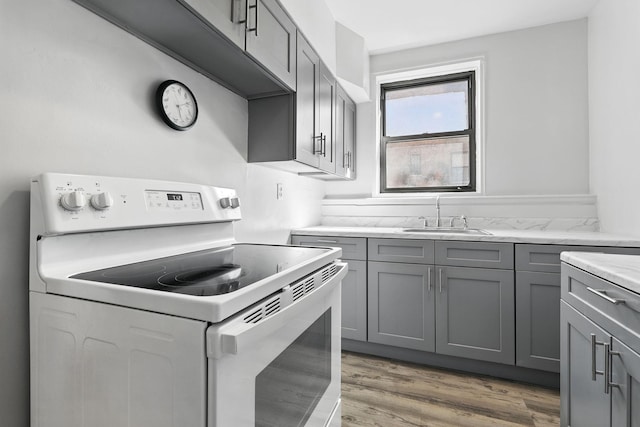 10 N Broadway Unit 3H, White Plains, NY 10601 - kitchen featuring white range with electric cooktop, a sink, gray cabinetry, and light wood finished floors
