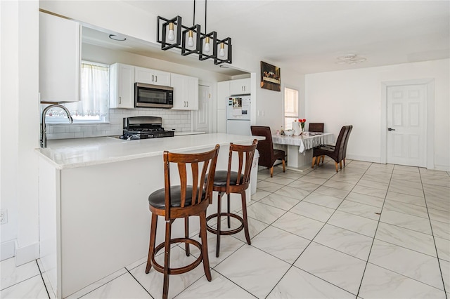 45 Cragmere Rd, Airmont, NY 10901 - kitchen featuring gas range oven, stainless steel microwave, freestanding refrigerator, light countertops, and backsplash