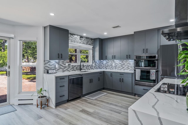 8 Hamilton Pl, Lake Grove, NY 11755 - kitchen with stainless steel appliances, gray cabinets, range hood, decorative backsplash, and light stone counters