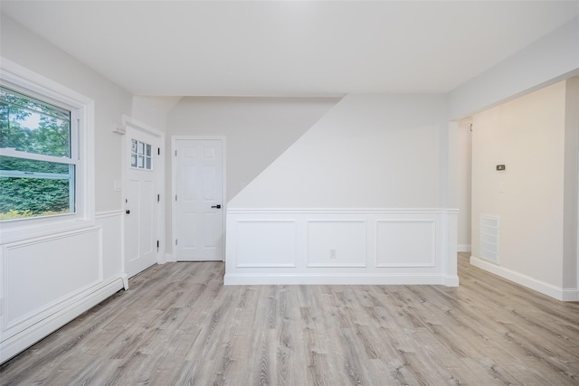 59 Burney Blvd, Mastic, NY 11950 - empty room featuring light wood-type flooring, a baseboard radiator, a wainscoted wall, and a decorative wall