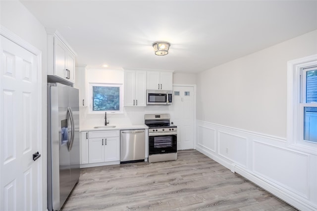 59 Burney Blvd, Mastic, NY 11950 - kitchen with appliances with stainless steel finishes, a sink, white cabinets, light countertops, and light wood finished floors