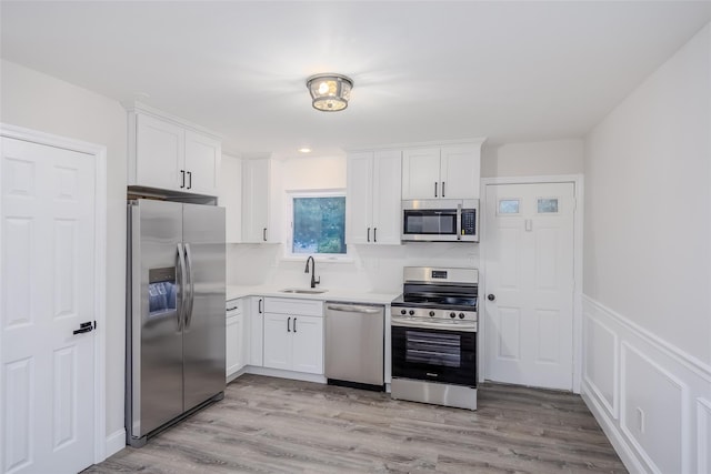 59 Burney Blvd, Mastic, NY 11950 - kitchen featuring stainless steel appliances, white cabinetry, a sink, light countertops, and light wood-style flooring