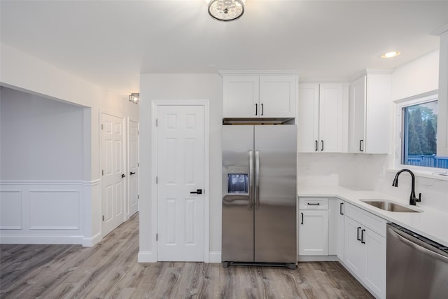 59 Burney Blvd, Mastic, NY 11950 - kitchen featuring stainless steel appliances, a sink, white cabinetry, light wood-style floors, and light countertops