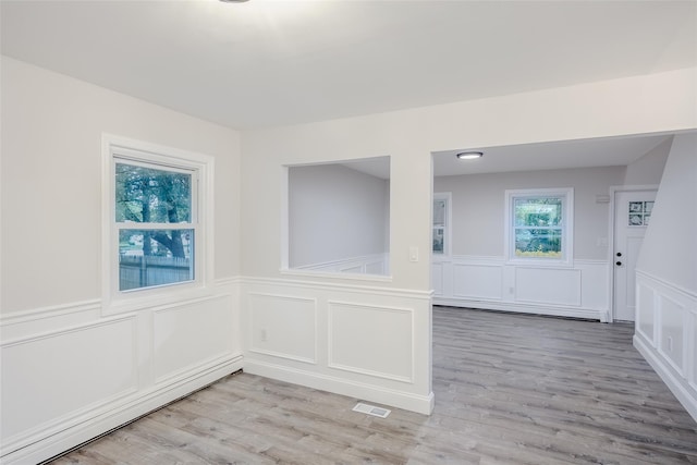 59 Burney Blvd, Mastic, NY 11950 - unfurnished room featuring a baseboard heating unit, wainscoting, a decorative wall, and light wood-type flooring