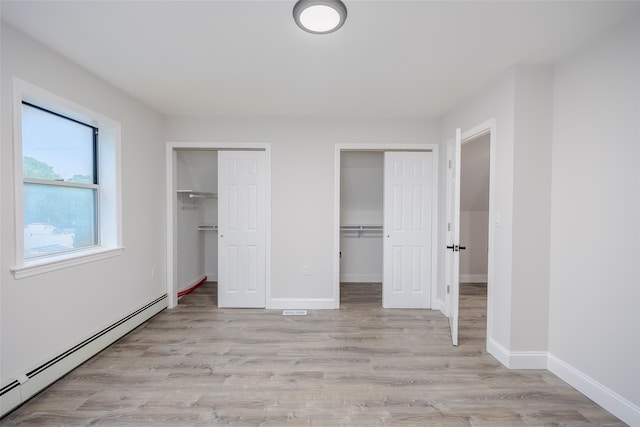 59 Burney Blvd, Mastic, NY 11950 - unfurnished bedroom featuring a baseboard radiator, two closets, light wood finished floors, and baseboards