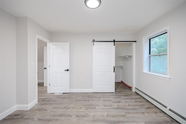 59 Burney Blvd, Mastic, NY 11950 - unfurnished bedroom with baseboard heating, light wood-style floors, a barn door, and baseboards