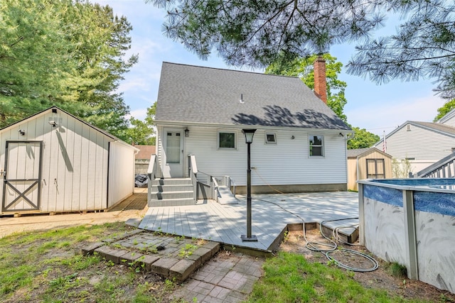 59 Burney Blvd, Mastic, NY 11950 - back of house with a storage unit, a chimney, an outdoor pool, roof with shingles, and a wooden deck