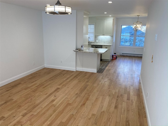 1626 Mogul Dr Unit 1626, Mohegan Lake, NY 10547 - kitchen featuring baseboard heating, a chandelier, decorative backsplash, light stone counters, and light wood finished floors