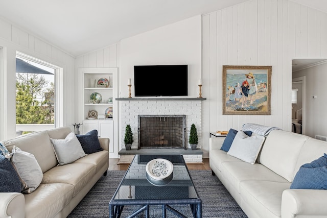 355 Dune Rd, Westhampton Beach, NY 11978 - living room with built in shelves, vaulted ceiling, wood finished floors, a brick fireplace, and wood walls