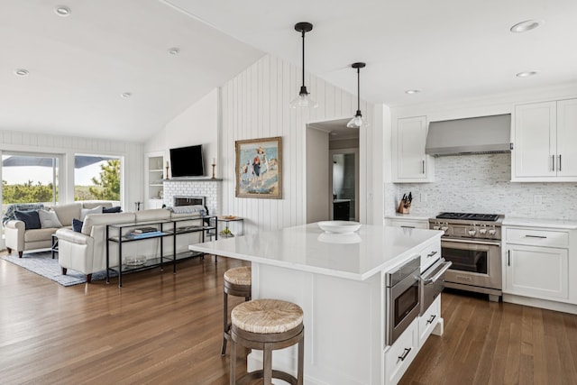 355 Dune Rd, Westhampton Beach, NY 11978 - kitchen with wall chimney exhaust hood, appliances with stainless steel finishes, lofted ceiling, dark wood-style flooring, and light countertops