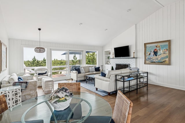 355 Dune Rd, Westhampton Beach, NY 11978 - dining space with vaulted ceiling, wood finished floors, a fireplace, built in shelves, and wooden walls