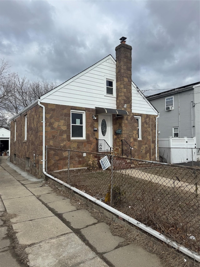 110 Terrace Ave, Elmont, NY 11003 - bungalow with stone siding, a fenced front yard, and a chimney