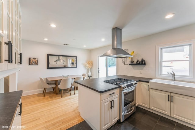 32 Henderson Ave, Port Washington, NY 11050 - kitchen with stainless steel gas range oven, island range hood, a sink, dark countertops, and a peninsula