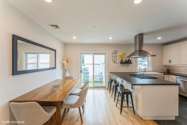32 Henderson Ave, Port Washington, NY 11050 - kitchen featuring island exhaust hood, dark countertops, plenty of natural light, recessed lighting, and white cabinets