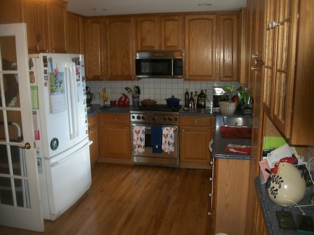 2713 Fox Rd, Baldwin, NY 11510 - kitchen with appliances with stainless steel finishes, dark countertops, backsplash, wood finished floors, and brown cabinets