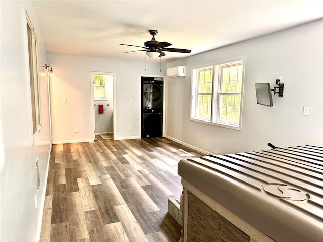 3206 Sharon Tpke, Millbrook, NY 12545 - bedroom featuring estacked washer and dryer, an AC wall unit, multiple windows, and wood finished floors