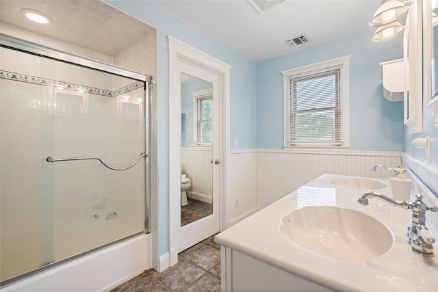 10 Stewart St, East Islip, NY 11730 - full bathroom featuring wainscoting, toilet, double vanity, enclosed tub / shower combo, and tile patterned flooring