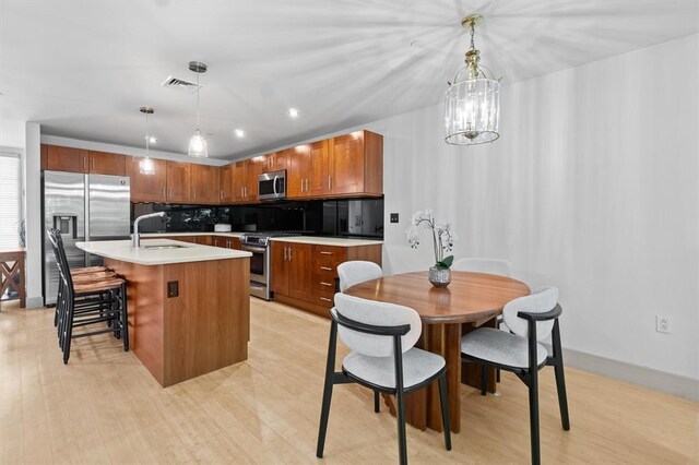 45 Main St Unit 3K, Hastings-On-Hudson, NY 10706 - kitchen featuring stainless steel appliances, a sink, tasteful backsplash, hanging light fixtures, and light countertops