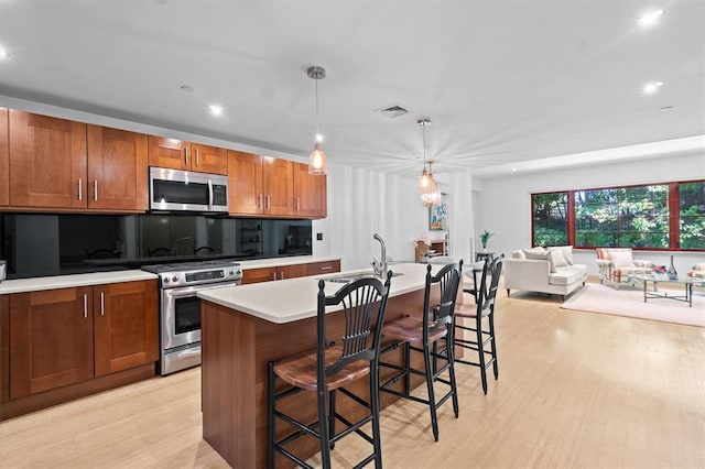 45 Main St Unit 3K, Hastings-On-Hudson, NY 10706 - kitchen featuring stainless steel appliances, a sink, light countertops, light wood finished floors, and brown cabinetry