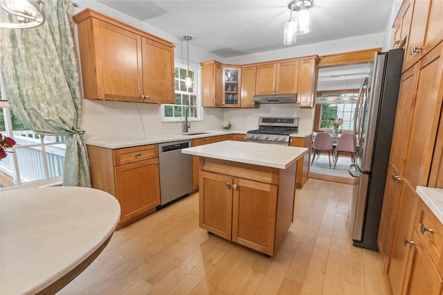16 Lyncrest Rd, Cortlandt Manor, NY 10567 - kitchen with appliances with stainless steel finishes, under cabinet range hood, light wood-style floors, decorative light fixtures, and a kitchen island