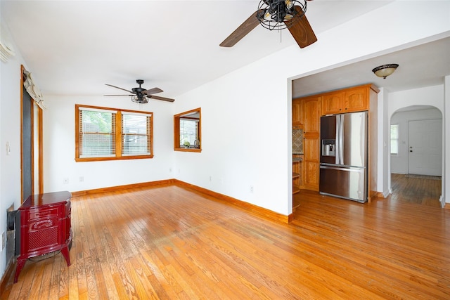 924 Violet Ave, Hyde Park, NY 12538 - unfurnished living room with a ceiling fan, arched walkways, light wood-style flooring, a wood stove, and baseboards