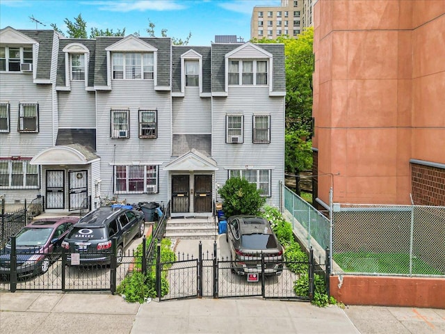 977 E 179th St, Bronx, NY 10460 - townhome / multi-family property with a gate, a shingled roof, a fenced front yard, and mansard roof