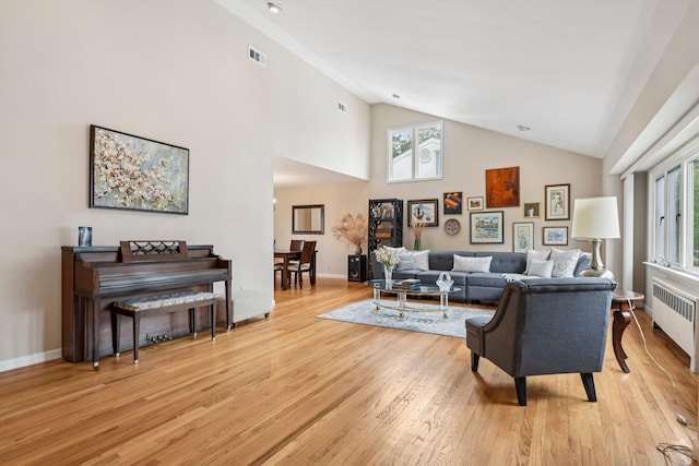 904 Woodmere Dr, North Woodmere, NY 11581 - living room with radiator heating unit, high vaulted ceiling, light wood finished floors, healthy amount of natural light, and baseboards