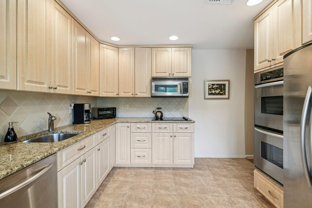 904 Woodmere Dr, North Woodmere, NY 11581 - kitchen with stainless steel appliances, a sink, backsplash, light stone counters, and light brown cabinets