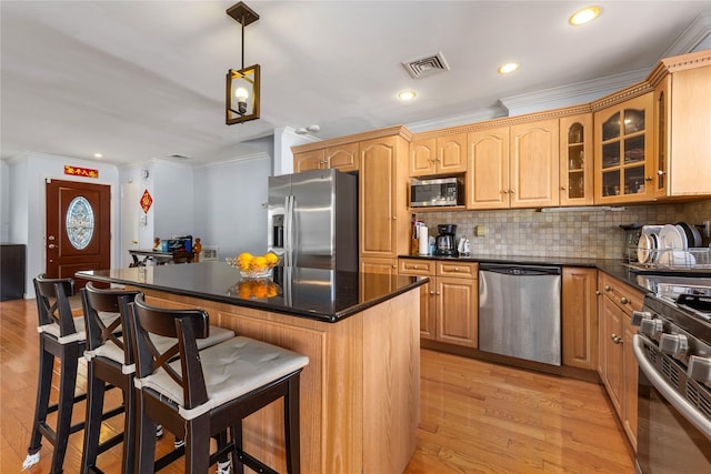 30 Eaton Rd, Syosset, NY 11791 - kitchen with appliances with stainless steel finishes, crown molding, a kitchen breakfast bar, light wood-style flooring, and a kitchen island